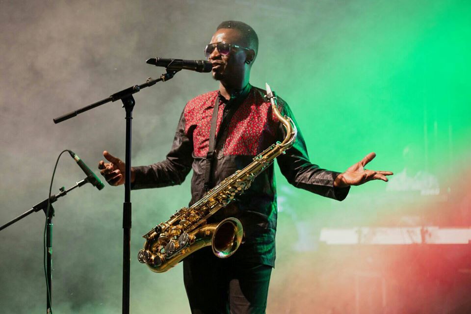 Juma Tutu performing on stage with saxophone and microphone